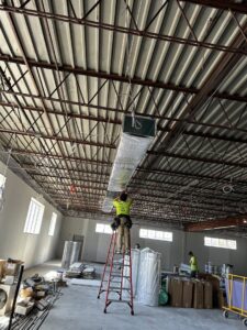 A technician installing large HVAC ductwork in a commercial building by Legendary Mechanical LLC in Toms River, NJ.
