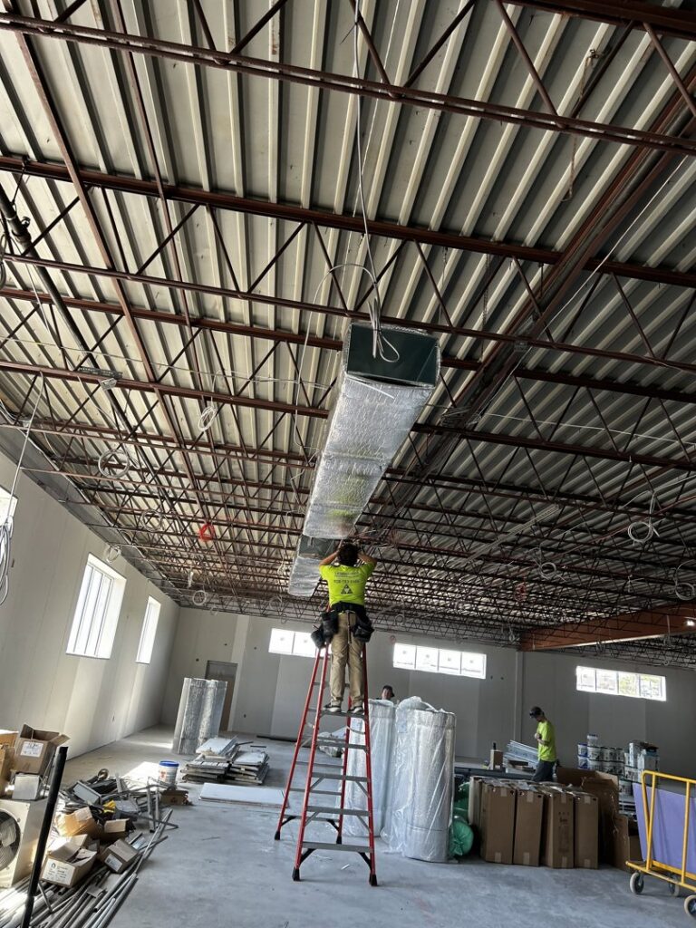 A technician installing large HVAC ductwork in a commercial building by Legendary Mechanical LLC in Toms River, NJ.