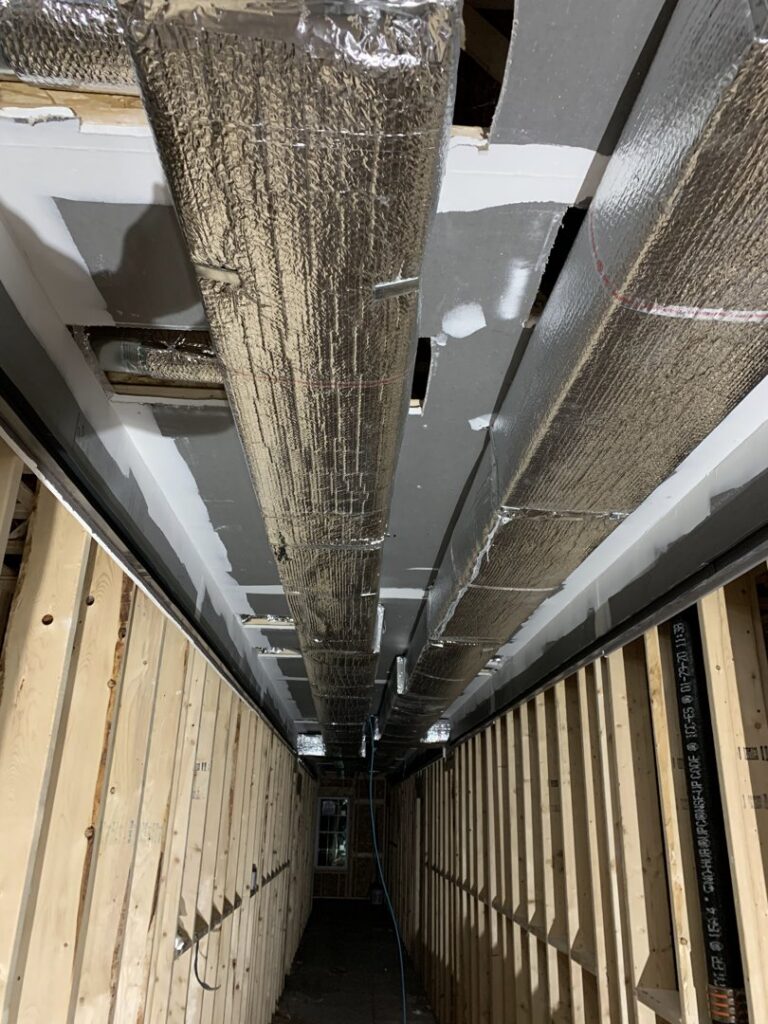 HVAC ductwork installation in a hallway during construction by Atmos HVAC in Quincy, MA.