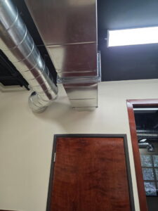 Detailed view of exposed metal HVAC ductwork installation in a commercial hallway by Jons-Air in Carmel, IN.