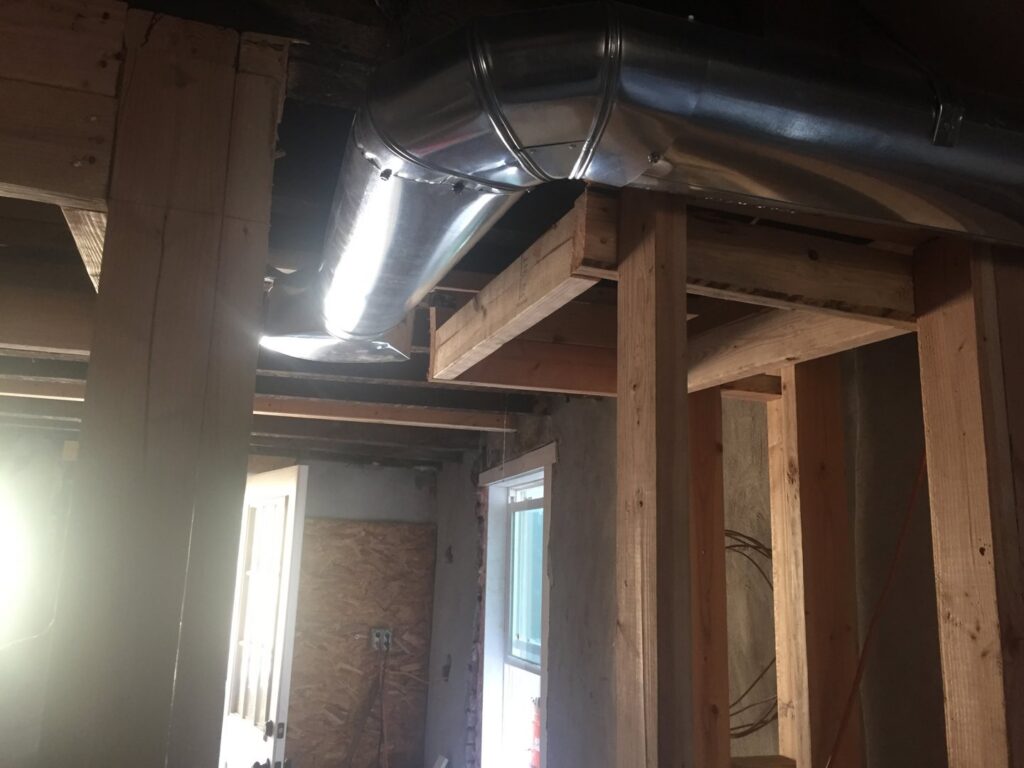 New round metal HVAC ductwork installed in a ceiling during construction by Air Done Right in Philadelphia, PA.