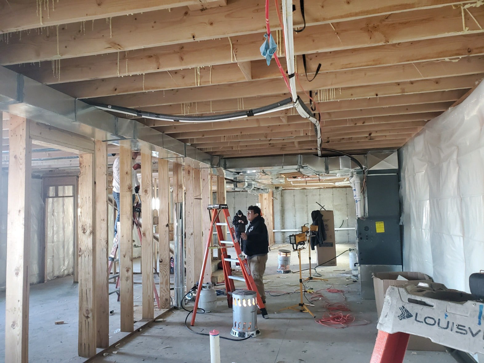 HVAC technicians installing ductwork in a new construction basement at a job site by All Seasons Heating & Cooling Inc in Idaho Falls, ID.
