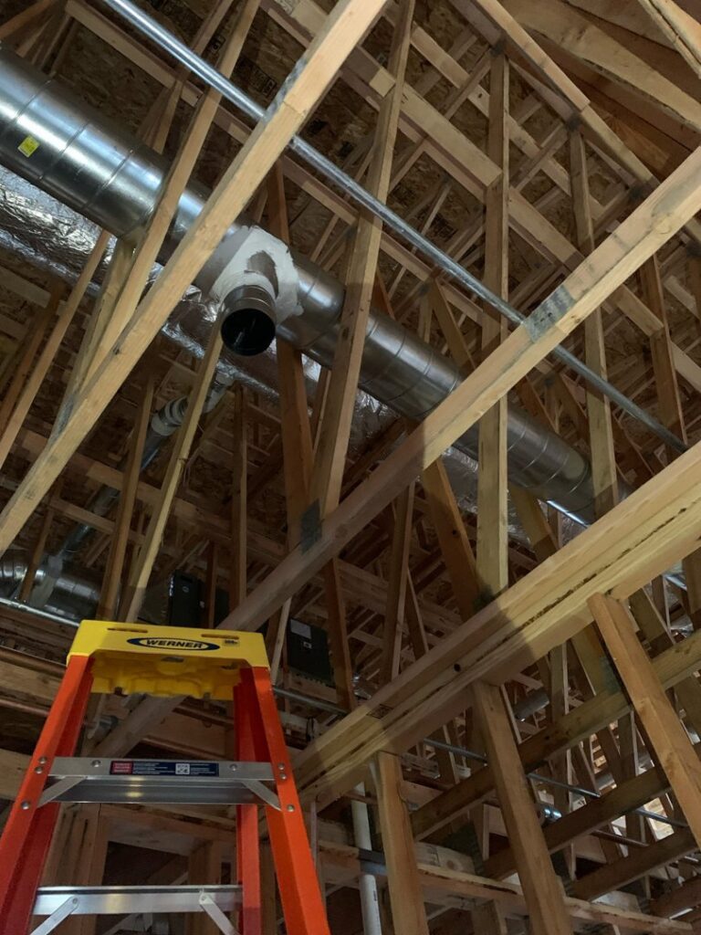 New HVAC ductwork being installed in the ceiling of a construction project by Alpine Heating in Eugene, OR.