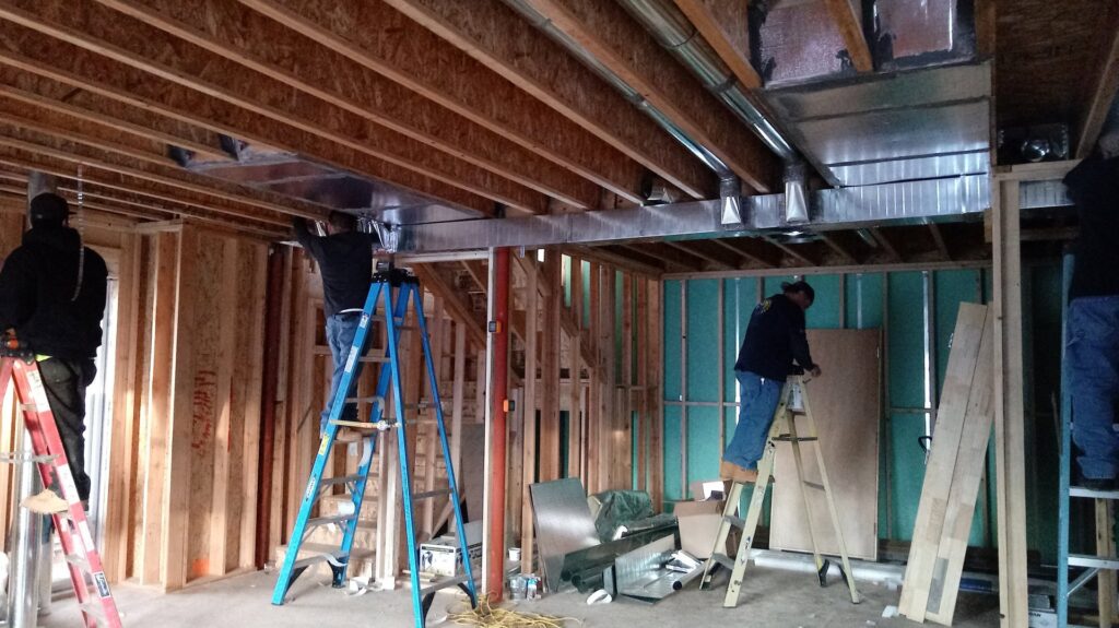 HVAC technicians installing large rectangular ductwork in a new construction building by Atmosphere Mechanical Heating And Air / Ventilation in Aurora, CO.