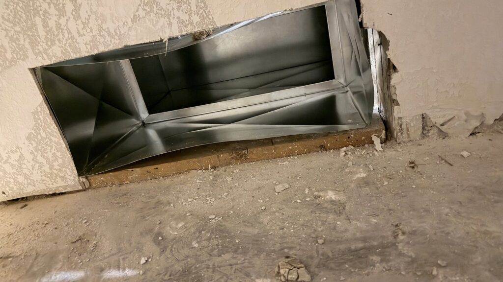 An open HVAC ductwork opening in a wall, showing the metal ducting during installation by The HVAC Doc in Rock Springs, WY