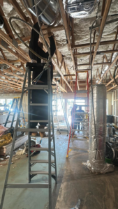 An HVAC technician installing new ductwork and wiring in a commercial building ceiling for Rosales Aire Inc. in Anaheim, CA.