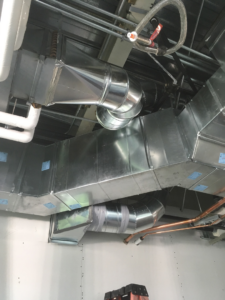 HVAC ductwork installation in progress with additional piping and a ladder at Mechanical Design & Service in Ogden, UT