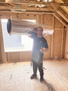 An HVAC technician installing ductwork in a new construction home for Southern Comfort Heating/Cooling/Gas in Fayetteville, NC.