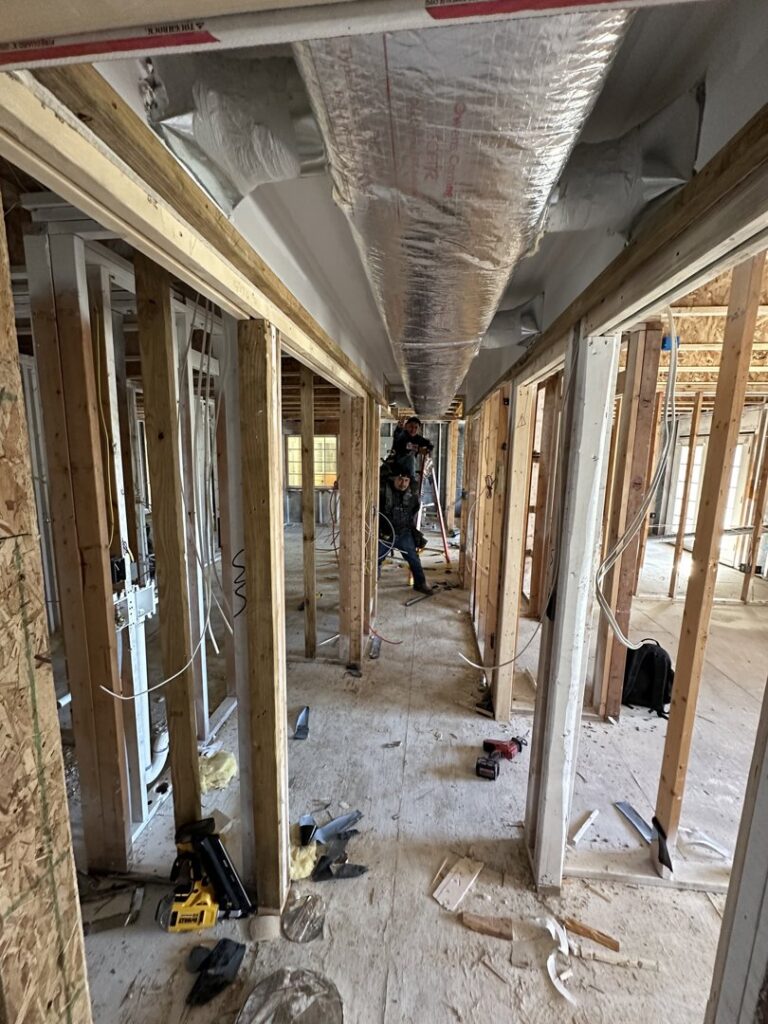 HVAC technicians from Federal Heating & Cooling installing ductwork in a framed hallway during new construction in Dresden, OH.