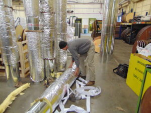 A technician insulating large HVAC ductwork in a workshop for Eastergard HVAC in Greenville, SC.