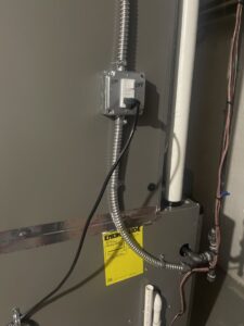 Electrical wiring and an on/off switch connected to an HVAC unit, showing installation work by Crain Heating and Cooling in Jeffersonville, IN.