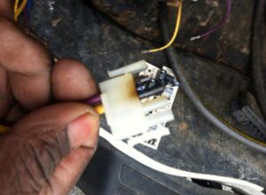 A technician's hand holding an electrical connector during an HVAC repair, demonstrating work by Johnson's Heating and Cooling in Clarksville, TN.