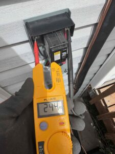 An Advanced Home Services technician performing electrical diagnostics on an HVAC system in Rigby, ID.