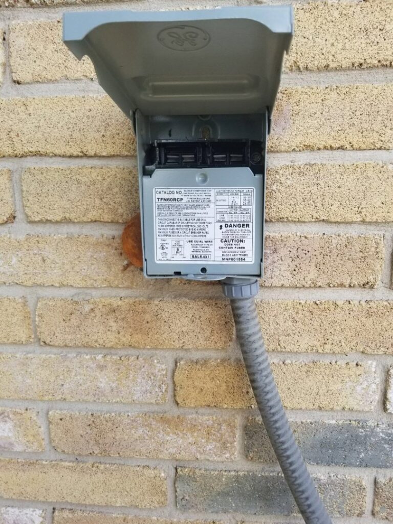 An outdoor electrical disconnect box for an HVAC unit, showing part of a service by Airtegrity Comfort Solutions in San Antonio, TX