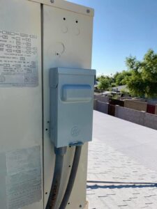 An electrical disconnect box for a rooftop HVAC unit, showing part of an installation by Arizaz Heating & Cooling in Chandler, AZ.