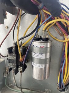 Close-up of HVAC electrical wiring and a capacitor inside an outdoor unit during repair by Arctic Desert Cooling & Heating in Concord, NC