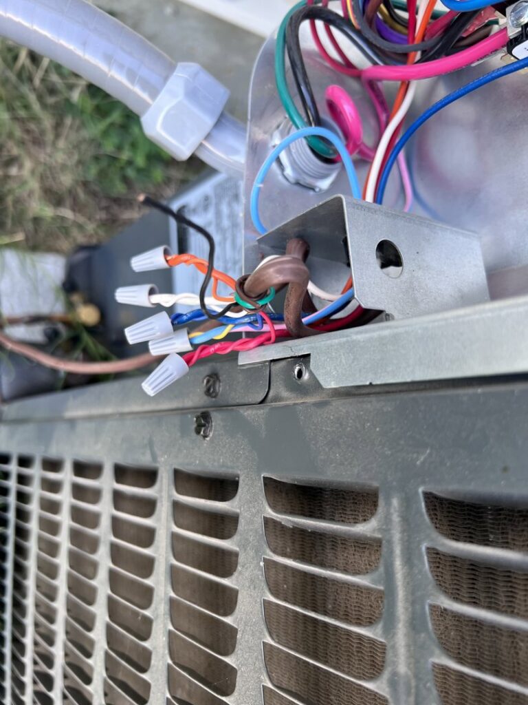 Close-up of electrical wiring with wire nuts inside an outdoor HVAC unit, showing repair work by Quistian Lighting in Arlington, TX