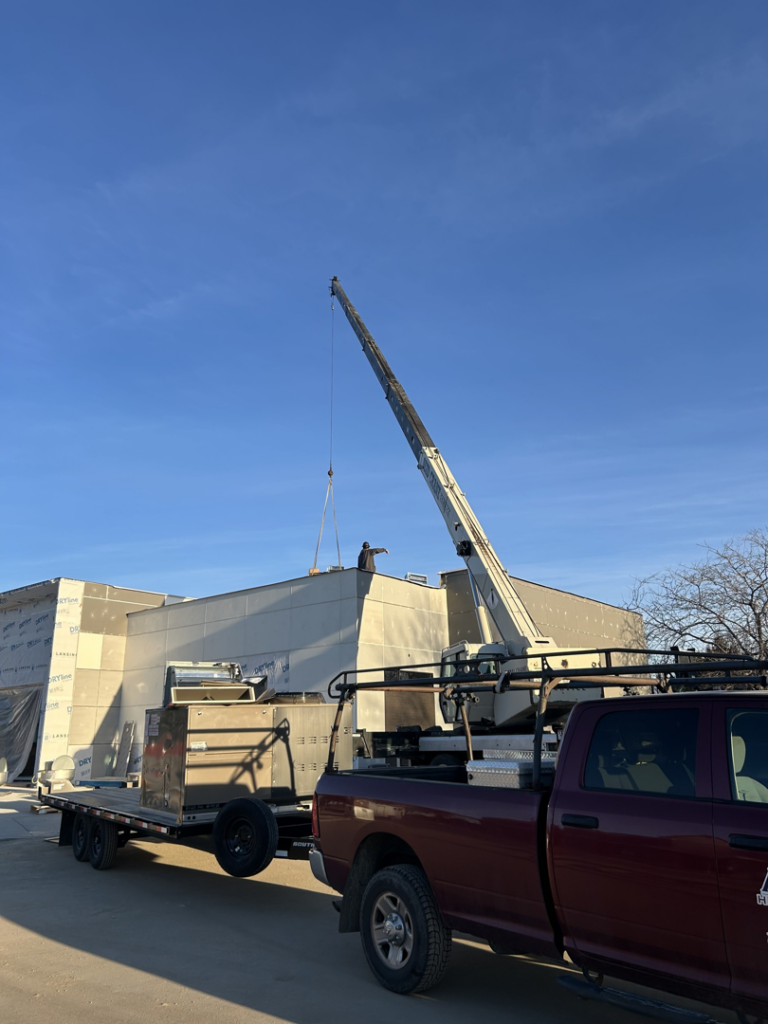 A crane lifting HVAC equipment onto a building during installation by Atlas Heating and Air, LLC in Talent, OR
