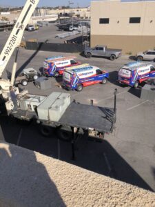HVAC equipment being delivered by crane with company vans from 32 Degrees Heating and Air Conditioning in Las Vegas, NV