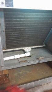 A close-up view of an HVAC evaporator coil and drain pan, demonstrating service expertise by AirHero.Pro in Lafayette, LA.
