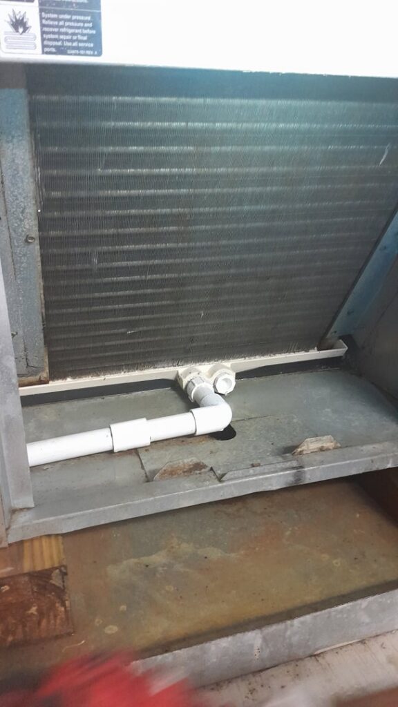 A close-up view of an HVAC evaporator coil and drain pan, demonstrating service expertise by AirHero.Pro in Lafayette, LA.