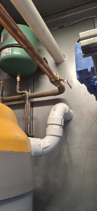 An HVAC expansion tank and drainage piping connected to a heating unit by J Hannah Mechanical Inc in Saco, ME.