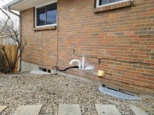 Exterior HVAC venting and piping on a brick residential building, installed by Thin Air Heating and Cooling in Arvada, CO.