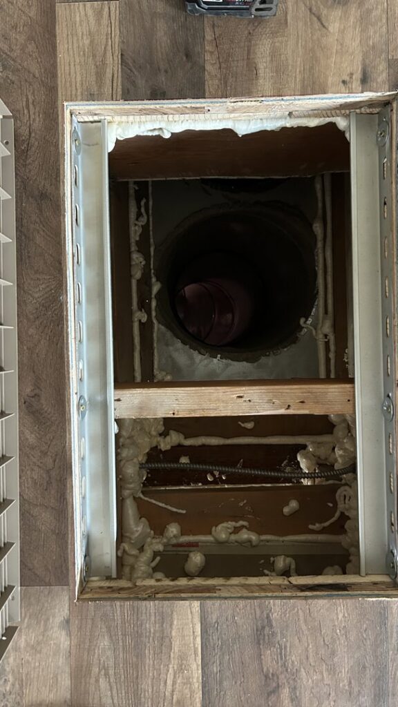 Close-up view of HVAC floor ductwork with insulation foam, indicating installation or repair by Service Kings Heating and Air in Jamestown, ND.