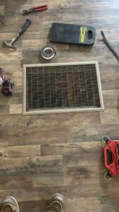 HVAC floor vent surrounded by tools, indicating repair or installation work by Service Kings Heating and Air in Jamestown, ND.