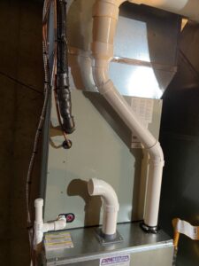 An indoor HVAC furnace and air handler unit with ductwork and piping installed by F & S Williams in Lafayette, IN.