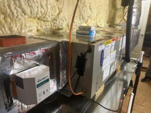 An indoor HVAC furnace or air handler unit with ductwork and insulation, installed by Heads Heating & Air Conditioning in Theodore, AL.