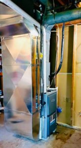 A newly installed HVAC furnace and extensive ductwork in a utility space by Adams Heating and Cooling in Schenectady, NY