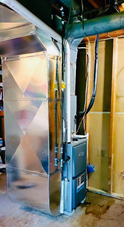 A newly installed HVAC furnace and extensive ductwork in a utility space by Adams Heating and Cooling in Schenectady, NY