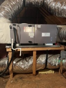 An HVAC furnace and insulated ductwork installed on a wooden platform in an attic by Advance Heating & Air, Inc. in Sumter, SC.