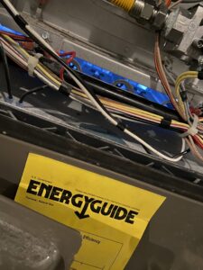 Electrical components and wiring inside an HVAC furnace with an Energy Guide sticker by McNeal and Sons Electrical and HVAC in Birmingham, AL.