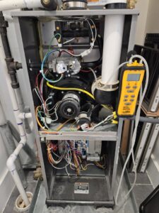 An open HVAC furnace unit showing complex electrical wiring and a diagnostic tool, serviced by GEN3 Electric & HVAC in Philadelphia, PA.