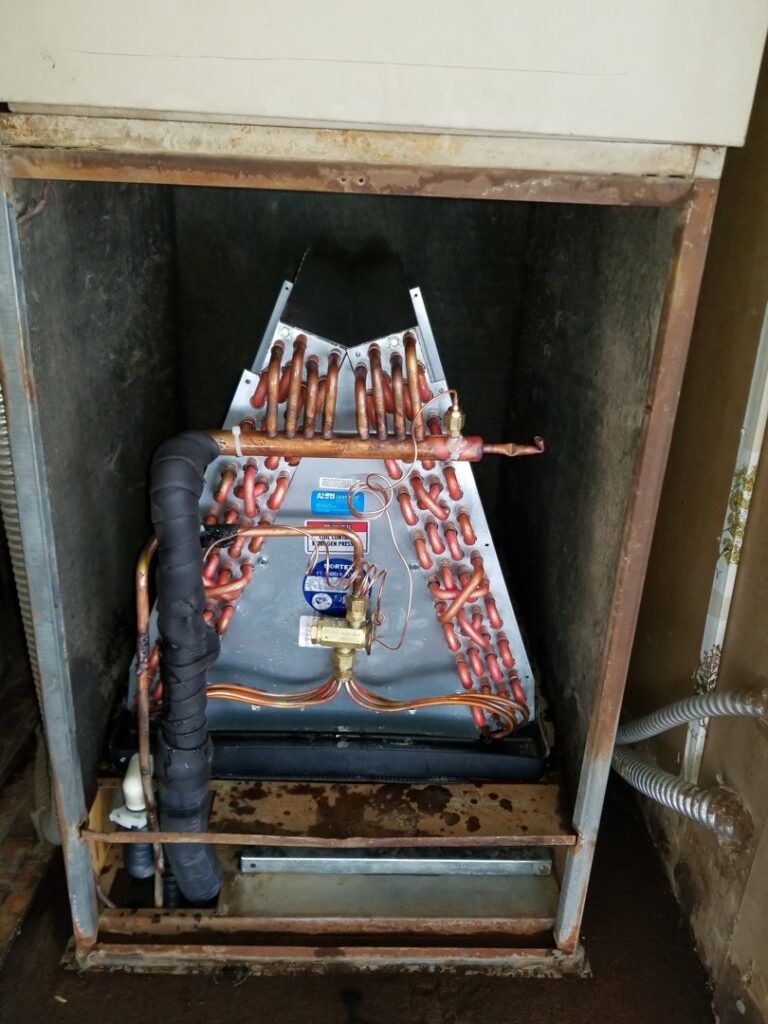An open HVAC furnace showing the evaporator coil and copper lines during an inspection by Kade Mechanical in Phoenix, AZ.