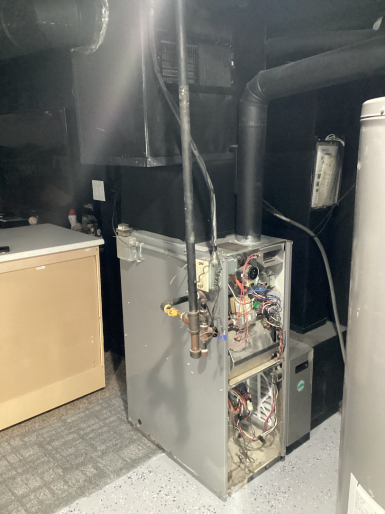 An HVAC technician inspecting the internal components of a furnace unit by Guzman Heating & Cooling in Milwaukee, WI.