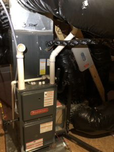 An indoor Goodman HVAC furnace unit with ductwork and piping, installed by QS HVAC LLC in Indianapolis, IN.