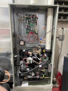 Internal view of an HVAC furnace showing wiring and control board during service by Mammoth Heating in Wasilla, AK.