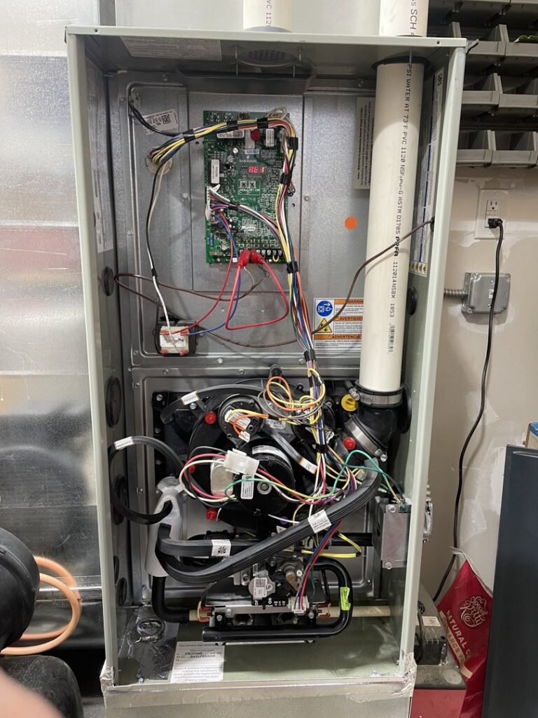 Internal view of an HVAC furnace showing wiring and control board during service by Mammoth Heating in Wasilla, AK.