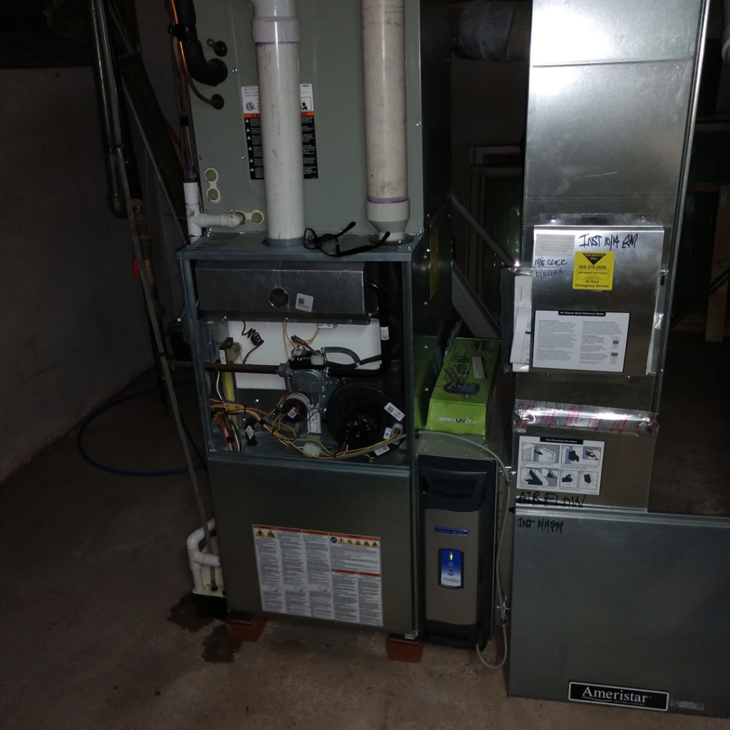 An HVAC furnace system with the access panel open, showing internal components during service by SM Heating and Cooling in Rochester, NY