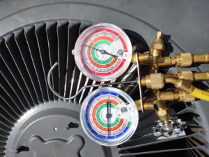 HVAC technician using gauges to service an outdoor air conditioning unit for Pettry Plumbing Heating & Air Inc in Bentonville, AR