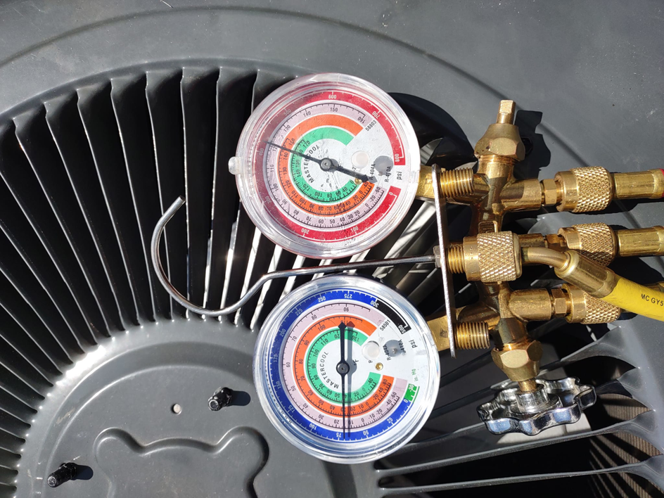 HVAC technician using gauges to service an outdoor air conditioning unit for Pettry Plumbing Heating & Air Inc in Bentonville, AR