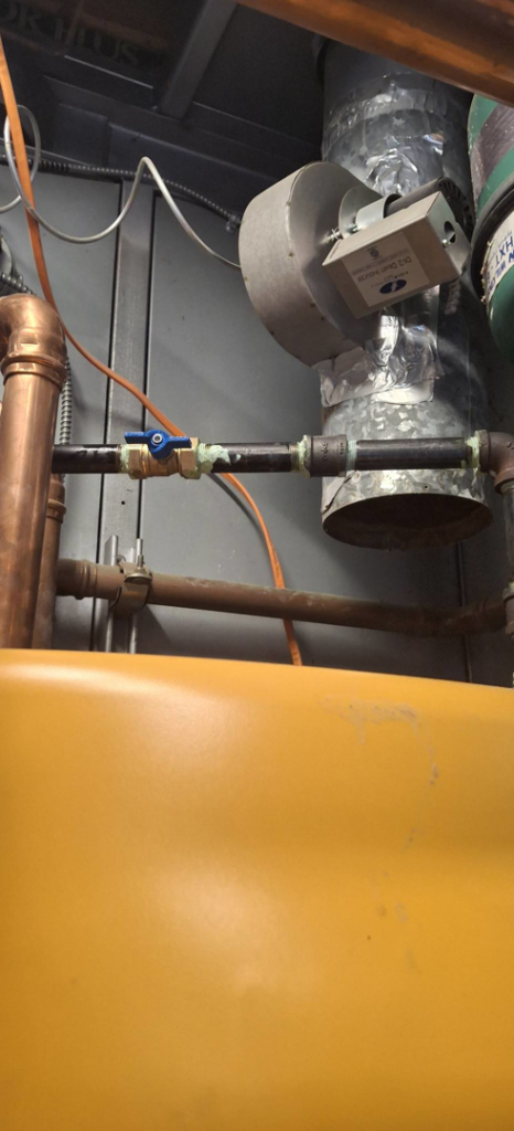 A commercial heating system with a large boiler tank, copper piping, and ductwork, serviced by J Hannah Mechanical Inc in Saco, ME.