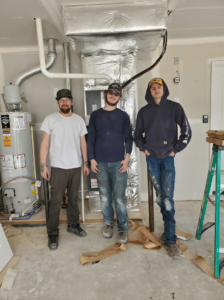 Three HVAC technicians standing in front of a newly installed furnace and ductwork by Integrity Heating And Air LLC in Nampa, ID