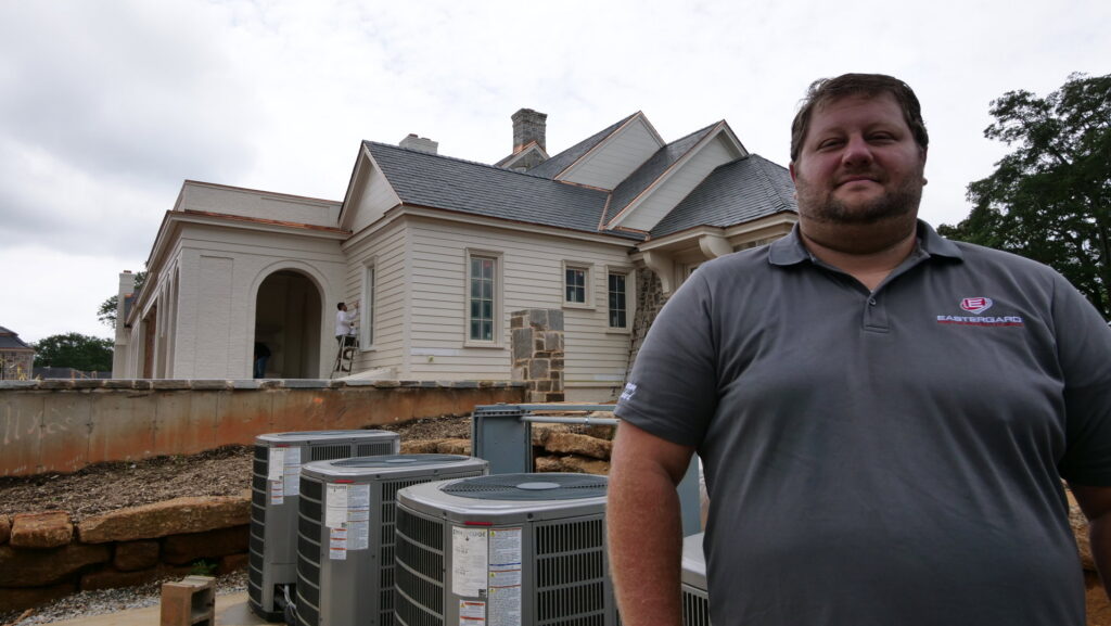 New HVAC units installed at a construction site by Eastergard HVAC in Greenville, SC, with a team member in the foreground.