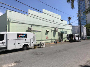 An Air Source, LLC service van parked at a job site with outdoor HVAC units and a ladder in Honolulu, HI.