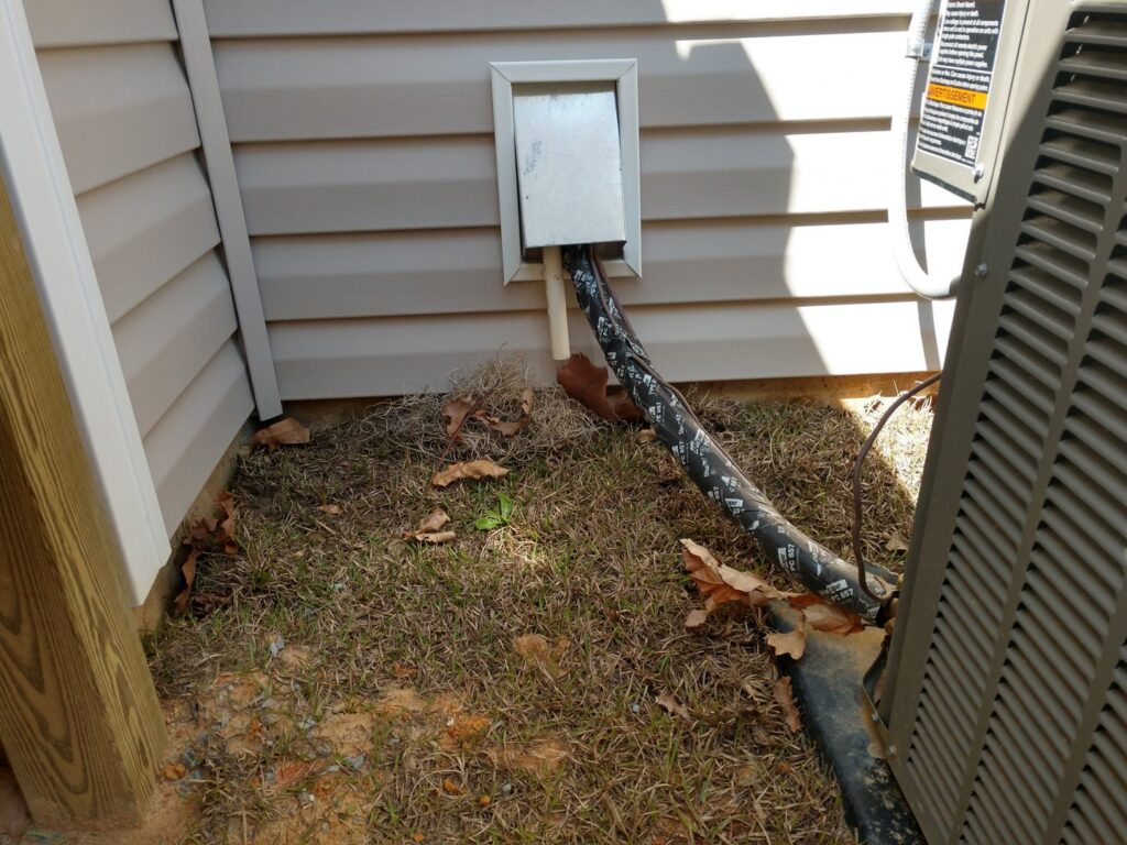 Close-up of HVAC lineset and electrical conduit professionally installed into a house by NAS Heating & Air in Fayetteville, NC.