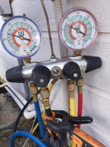 HVAC manifold gauges connected to refrigerant lines during a service call by Integrity Services Heating and Cooling in Madison, AL.